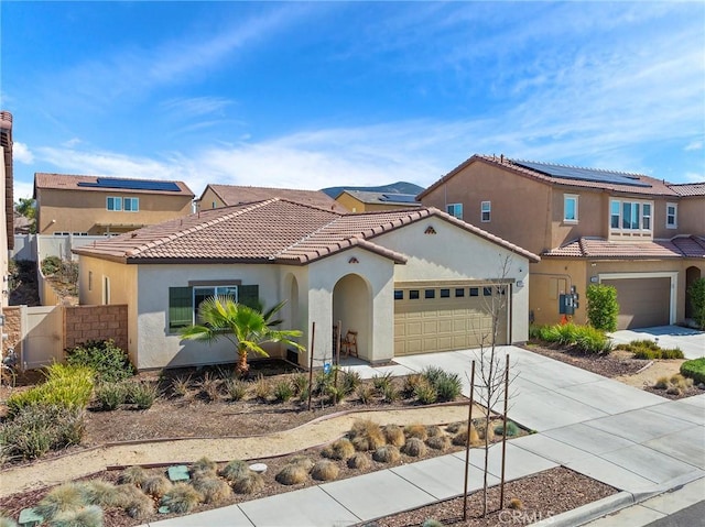 mediterranean / spanish house with stucco siding, fence, a garage, driveway, and a tiled roof