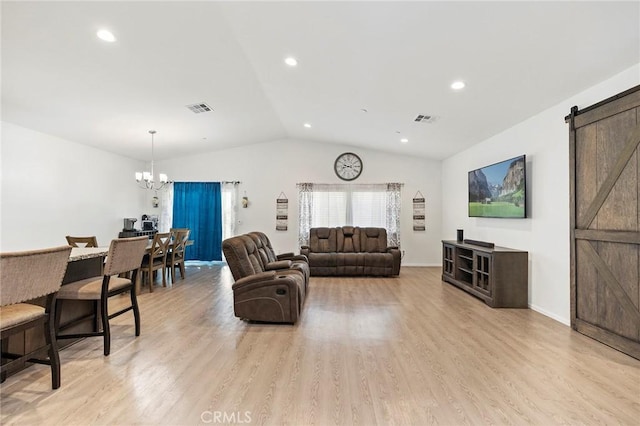 living room with vaulted ceiling, a barn door, visible vents, and light wood-style floors