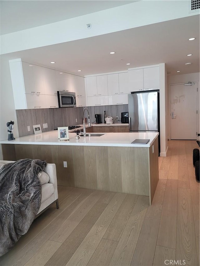 kitchen featuring stainless steel appliances, white cabinetry, a sink, and modern cabinets