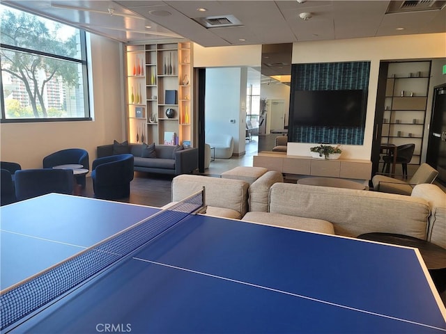 rec room with built in shelves, a healthy amount of sunlight, and visible vents