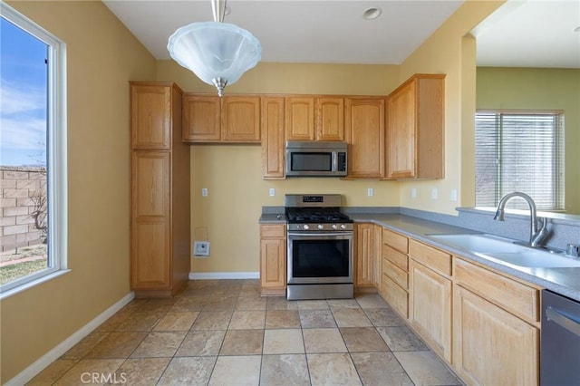 kitchen with pendant lighting, stainless steel appliances, a sink, and light brown cabinetry