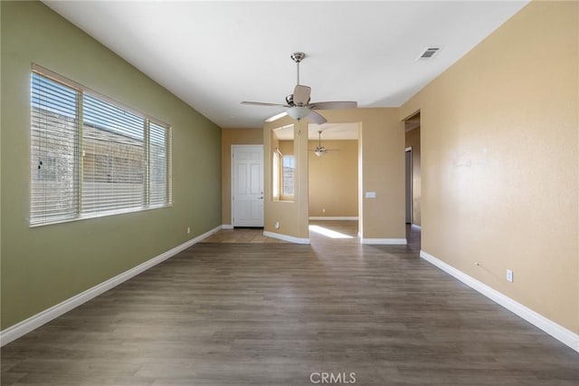 interior space featuring dark wood-style floors, baseboards, visible vents, and ceiling fan