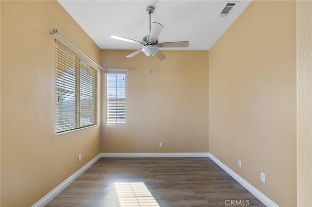 unfurnished room featuring dark wood-style flooring, visible vents, ceiling fan, and baseboards