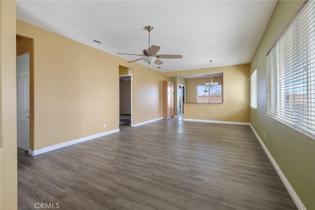 empty room featuring baseboards, visible vents, dark wood finished floors, and ceiling fan with notable chandelier