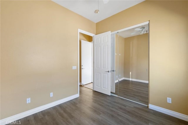 unfurnished bedroom with dark wood-style floors, ceiling fan, a closet, and baseboards