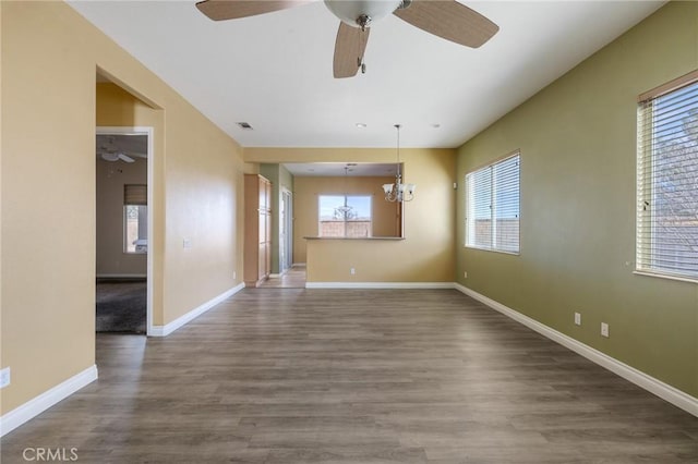 spare room with baseboards, visible vents, wood finished floors, and ceiling fan with notable chandelier