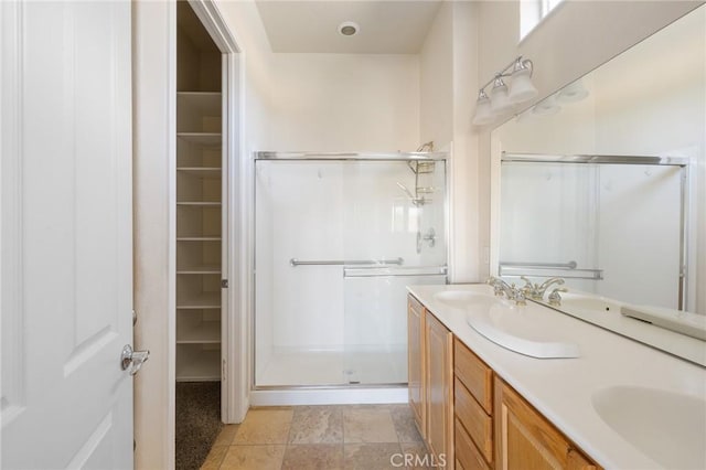 full bathroom with a spacious closet, double vanity, and a stall shower