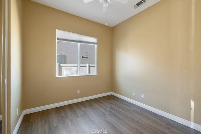 spare room with a ceiling fan, wood finished floors, visible vents, and baseboards