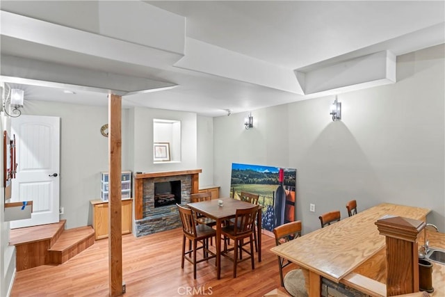 dining area with a stone fireplace and light wood-style flooring