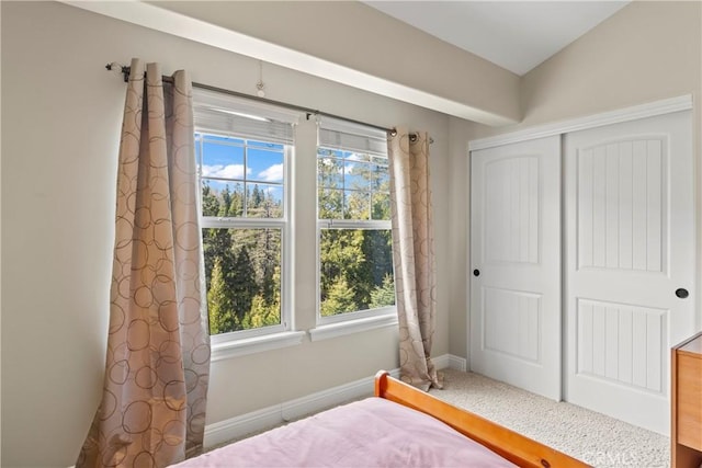 bedroom with lofted ceiling, a closet, carpet flooring, and baseboards