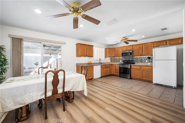 kitchen with stainless steel appliances, tasteful backsplash, visible vents, light wood-style floors, and a sink