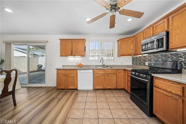 kitchen featuring a sink, black range with gas stovetop, dishwasher, tasteful backsplash, and stainless steel microwave