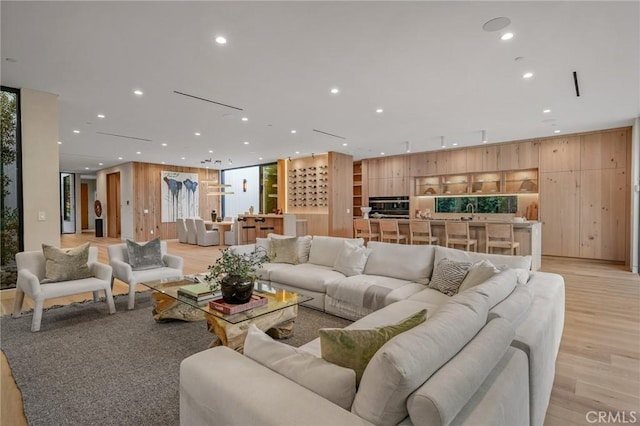 living area featuring wooden walls, recessed lighting, and light wood-style flooring