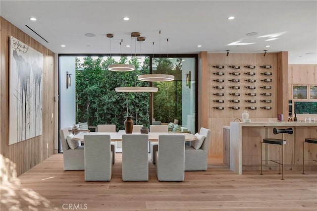 interior space with light wood-style flooring, wooden walls, floor to ceiling windows, and recessed lighting