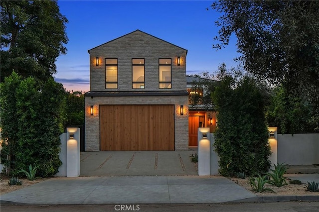 contemporary house with a fenced front yard, stone siding, an attached garage, and concrete driveway