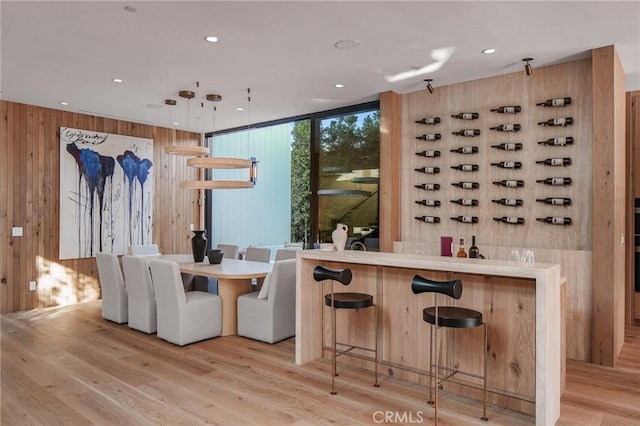 interior space with recessed lighting, wood walls, hanging light fixtures, and light wood-style flooring