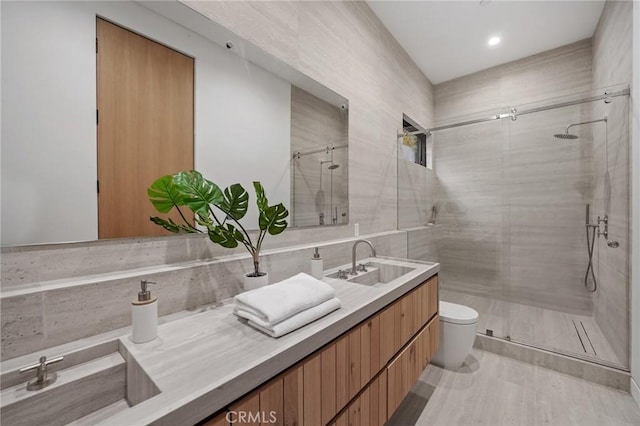 bathroom featuring a stall shower, a sink, toilet, and double vanity