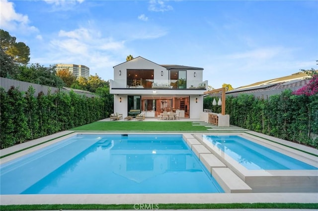 back of property featuring fence, a fenced in pool, stucco siding, a bar, and a patio area