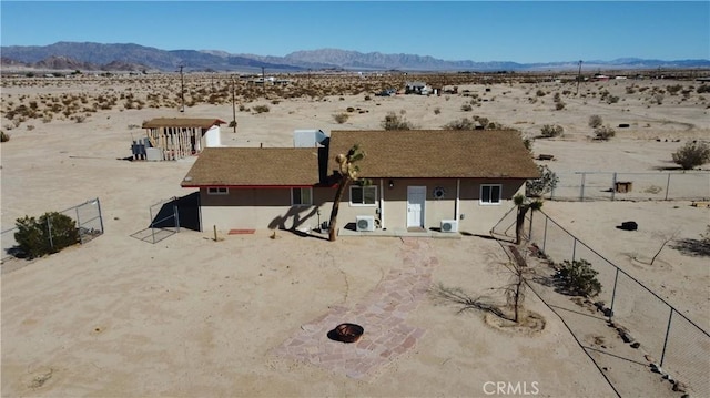 rear view of house featuring a desert view, stucco siding, a mountain view, and fence