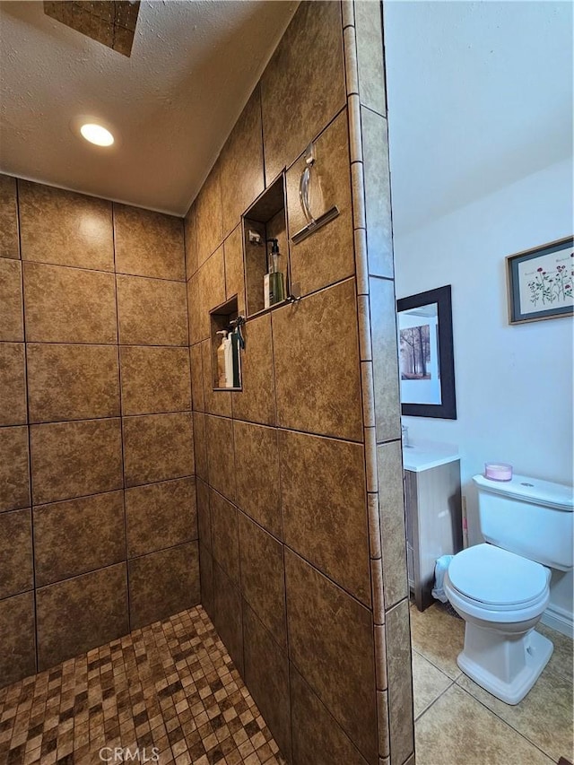 bathroom with a textured ceiling, a tile shower, toilet, and tile patterned floors