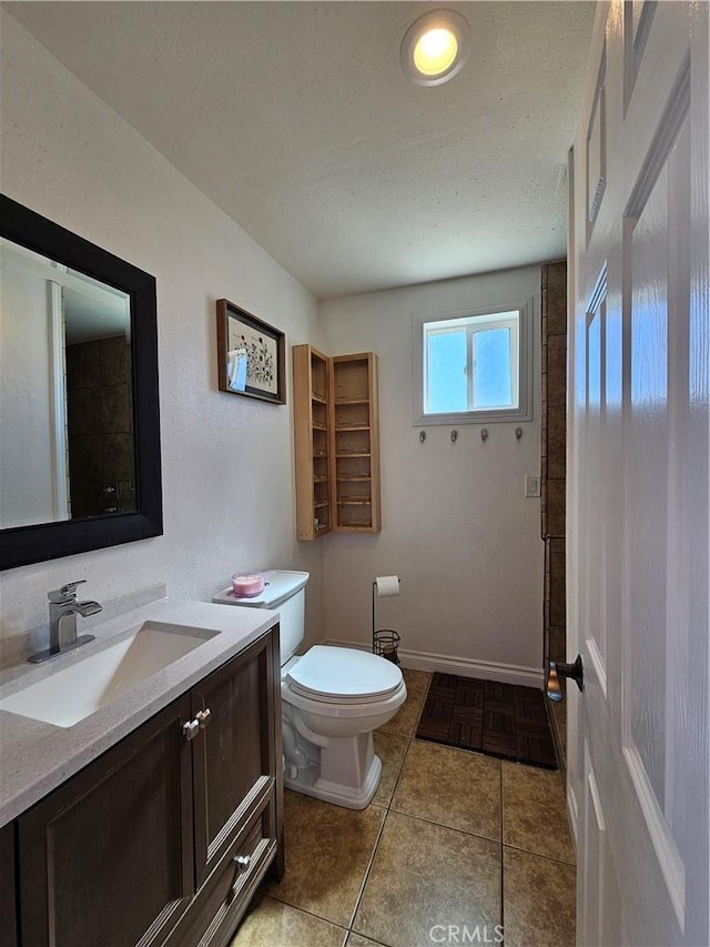 bathroom featuring toilet, vanity, a textured ceiling, and tile patterned floors