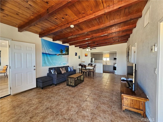 living area with ceiling fan, wood ceiling, beamed ceiling, and tile patterned floors