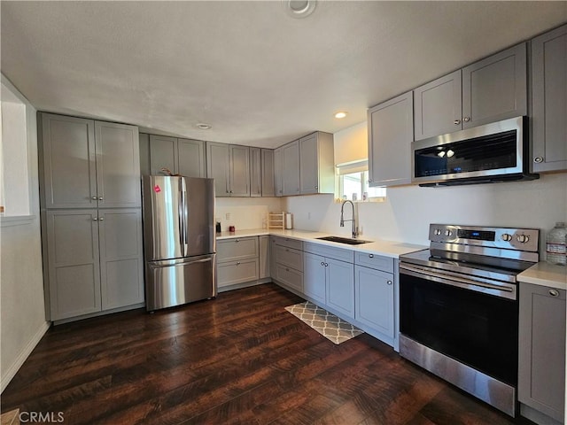 kitchen featuring gray cabinets, appliances with stainless steel finishes, light countertops, and a sink