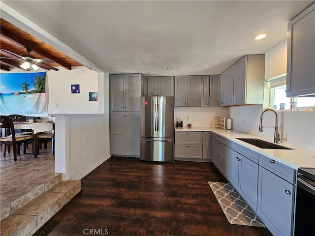 kitchen with gray cabinetry, dark wood-style flooring, a sink, light countertops, and freestanding refrigerator