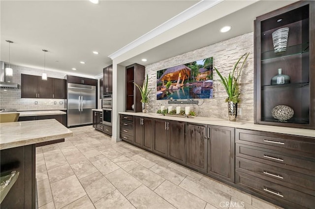 kitchen featuring dark brown cabinetry, stainless steel appliances, light countertops, decorative backsplash, and pendant lighting