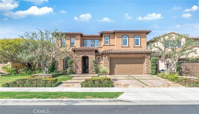 mediterranean / spanish home featuring a tiled roof, stucco siding, a garage, stone siding, and driveway