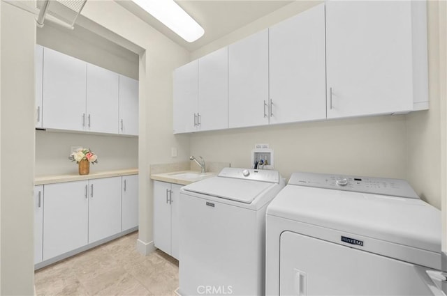 clothes washing area featuring cabinet space, a sink, and washing machine and clothes dryer