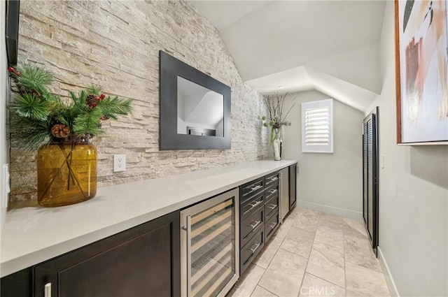 bar featuring vaulted ceiling, wine cooler, light tile patterned flooring, and baseboards