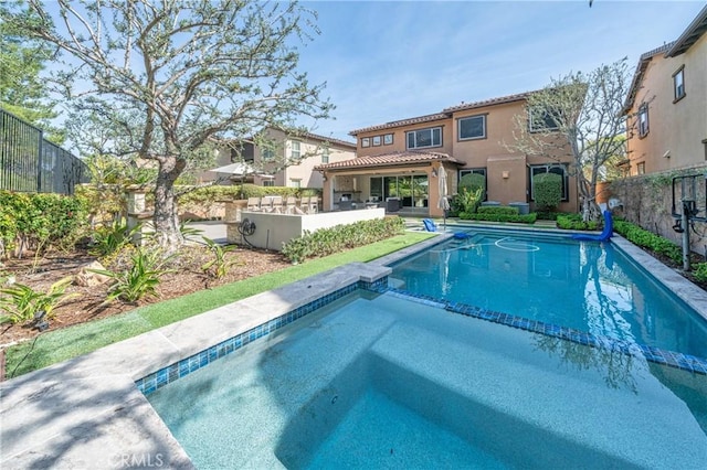 view of pool with a fenced backyard and a pool with connected hot tub