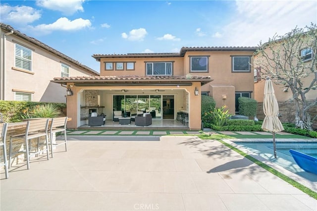 rear view of house featuring an outdoor pool, a patio, outdoor lounge area, and stucco siding