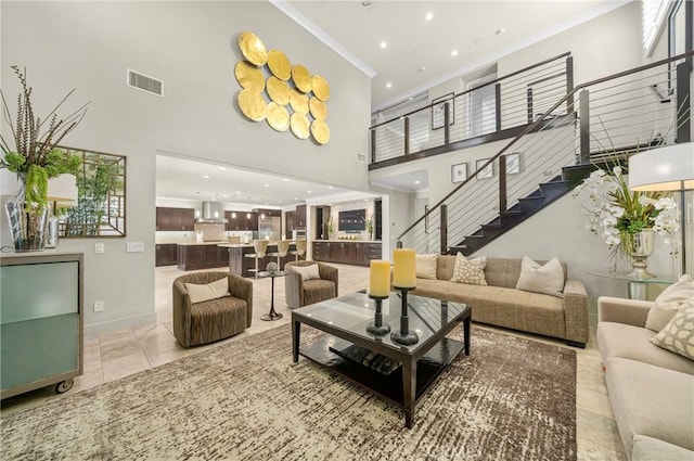 living room featuring visible vents, crown molding, light tile patterned floors, a towering ceiling, and stairs