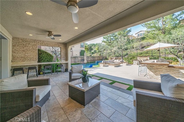 view of patio featuring outdoor dry bar, an outdoor hangout area, ceiling fan, a fenced backyard, and an outdoor pool