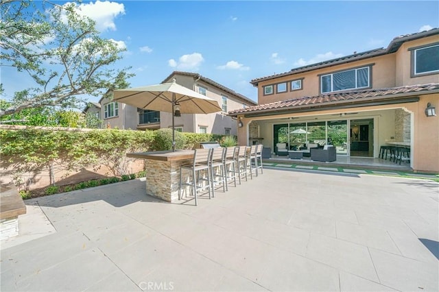 view of patio with outdoor dry bar and fence