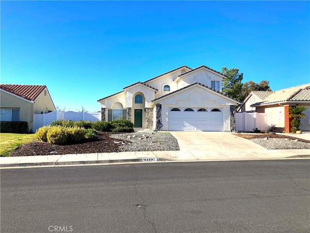 view of front facade with concrete driveway, an attached garage, fence, and stucco siding