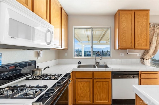 kitchen featuring brown cabinetry, white appliances, and a sink