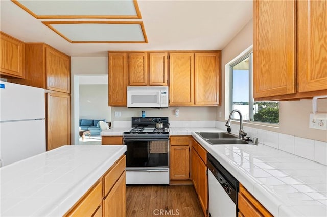 kitchen featuring white appliances, tile counters, dark wood-type flooring, and a sink