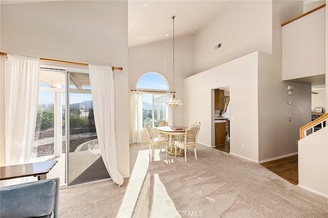 dining space with an inviting chandelier, baseboards, high vaulted ceiling, and carpet flooring