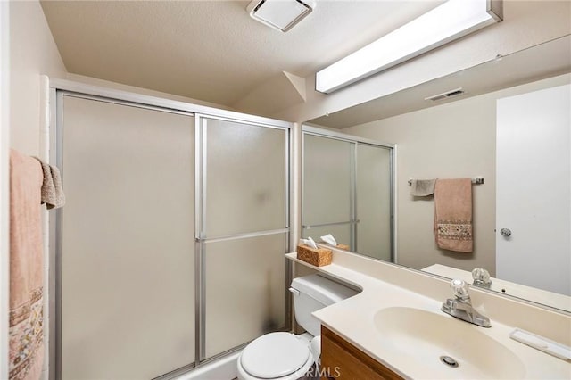 full bathroom featuring visible vents, a shower stall, toilet, and vanity