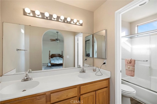 bathroom with toilet, double vanity, enclosed tub / shower combo, and a sink