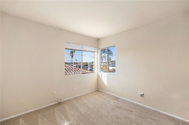 empty room with baseboards and light colored carpet