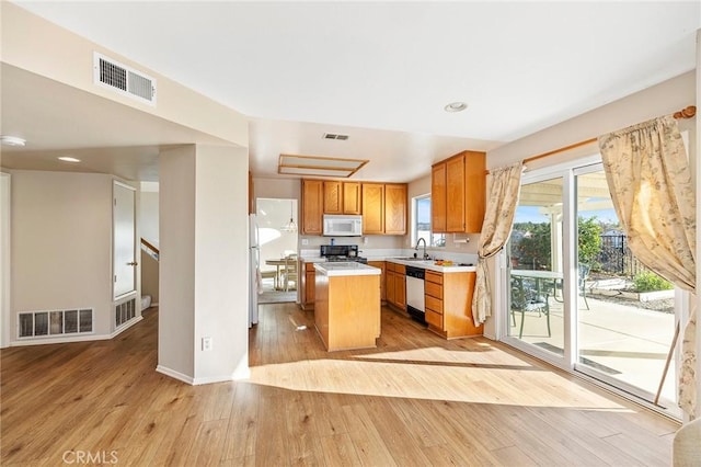 kitchen with light countertops, white appliances, visible vents, and a sink