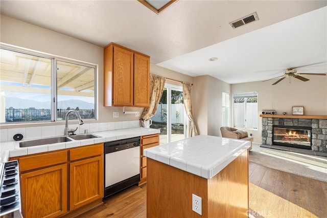 kitchen featuring tile countertops, a fireplace, a sink, visible vents, and dishwasher