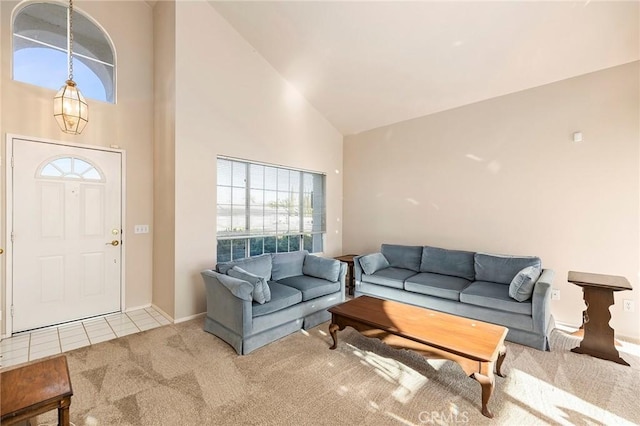 carpeted living area with high vaulted ceiling and tile patterned flooring