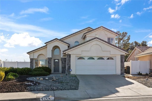 mediterranean / spanish-style home featuring a garage, concrete driveway, stone siding, fence, and stucco siding