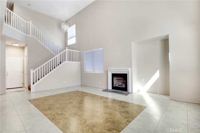 living room with stairs, a fireplace with raised hearth, a towering ceiling, and tile patterned floors