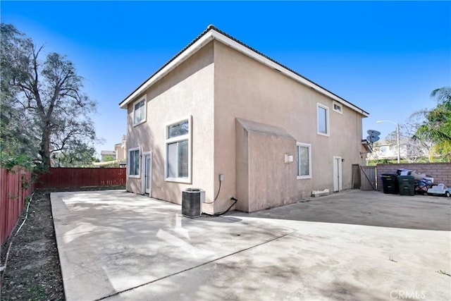 rear view of property with stucco siding, a fenced backyard, cooling unit, and a patio